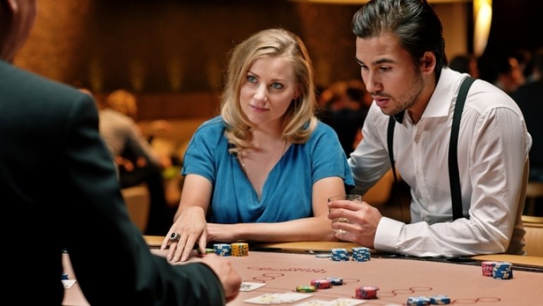 Мужчина и женщина напряженно играют в блэкджек против дилера в казино