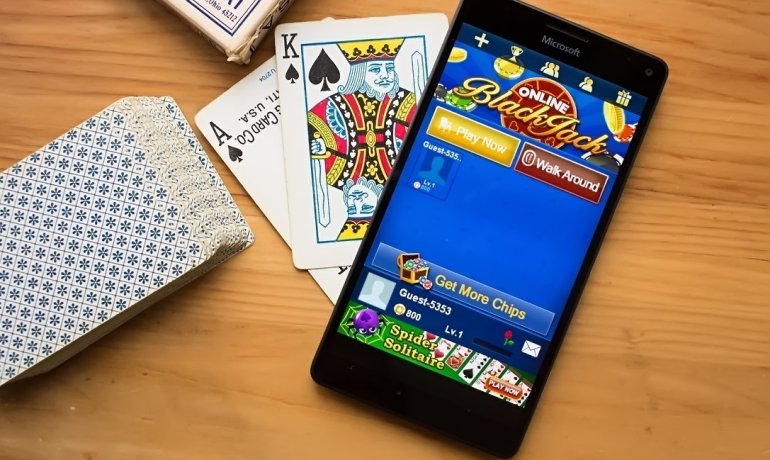 Колода карт и смартфон, на котором запущен онлайн покер