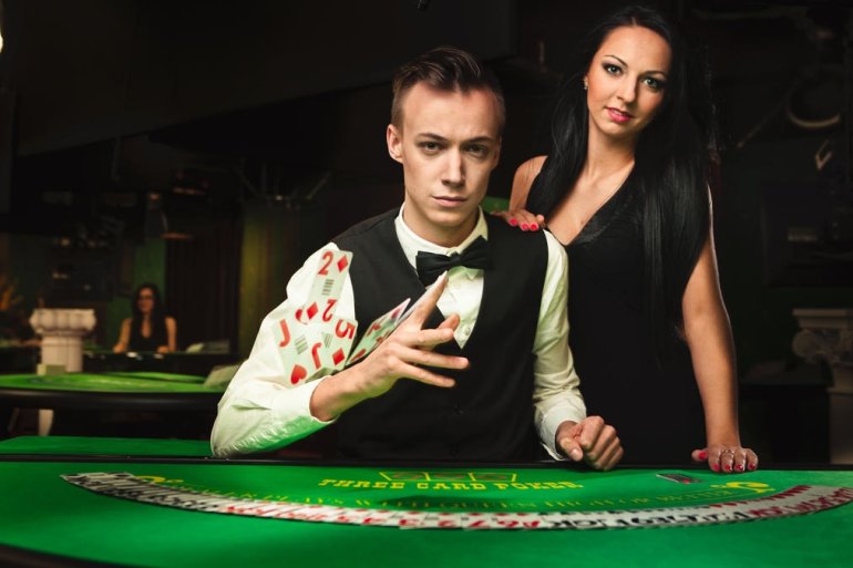 Молодой крупье и его сексуальная напарница за столом для игры в покер в ожидании клиентов