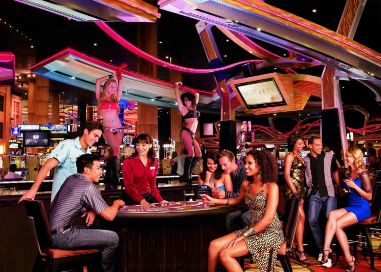 Люди выпивают, наслаждаются стриптизом и играют в азартные игры в дорогом казино