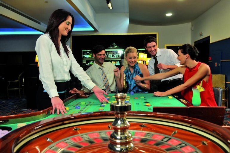 Привлекательная темноволосая девушка крупье ведет игру в рулетку для гостей казино