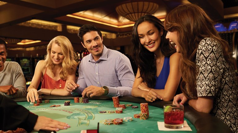 Молодой мужчина играет в блэкджек в компании троих привлекательных женщин в дорогом казино
