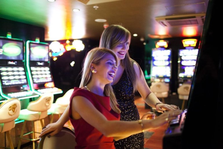 Две симпатичные блондинки играют на автомате в казино