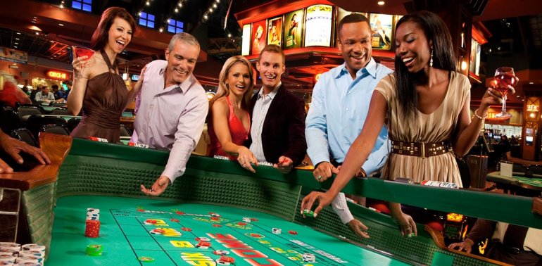 Веселая компания в дорогмо казино играет в крэпс и эмоционально поддерживает свои ставки