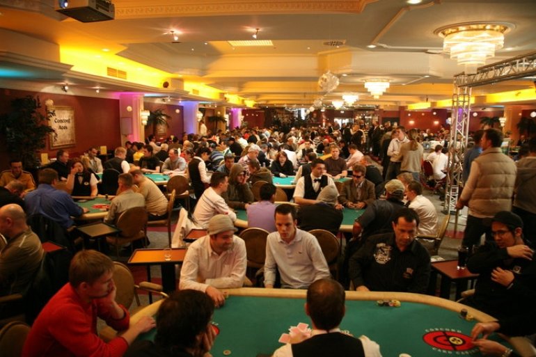 Клиенты казино Concord в игорном зале за покерными столами