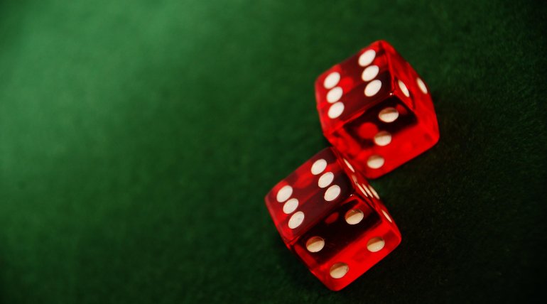 Пара красных кубиков для игры в кости на зеленом столе
