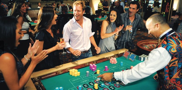 Компания играет в казино щза столом с пожилым лысым крупье