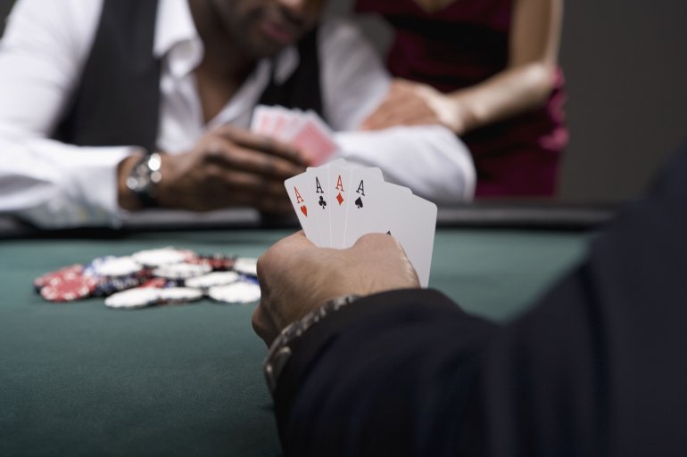 Руки игроков, которые держат карты за покерными столом