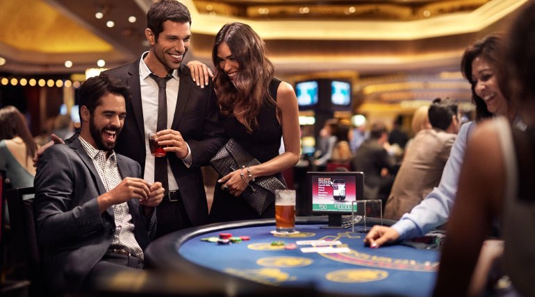 Двое азартных мужчин в строгих костюмах и красивая брюнетка в вечернем платье играют в блэкджек в казино вип-уровня