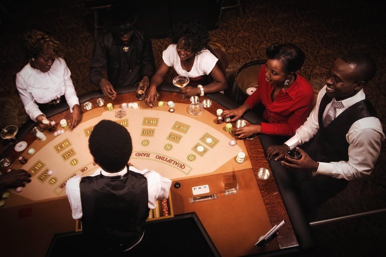Компания темнокожих людей за игрой в казино в компании крупье