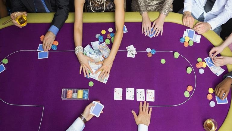 Вид сверху на игру за фиолетовым столом для покера