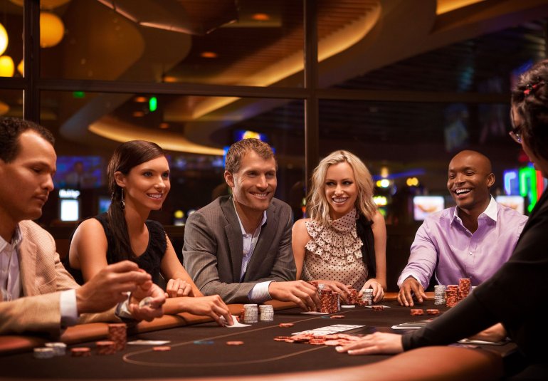 Симпатичные девушки и молодые мужчины при деньгах развлекаются в казино за игрой в покер