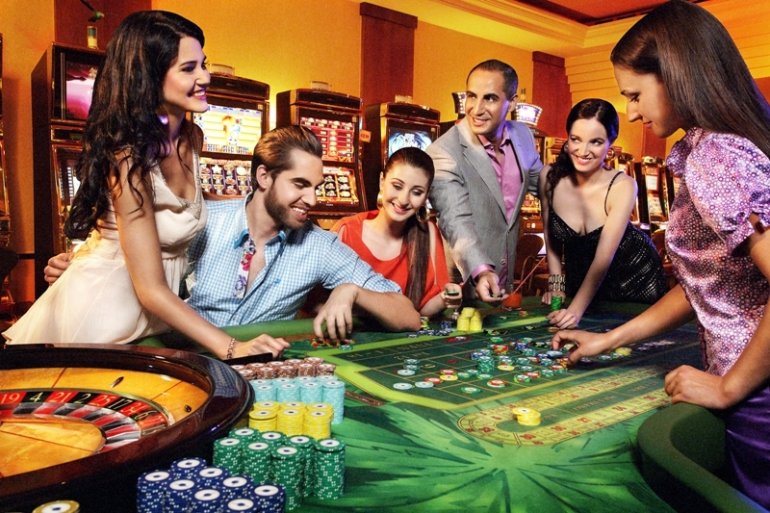 Двое восточных мужчин в окружении симпатичнх спутниц играют в рулетку в дорогом казино