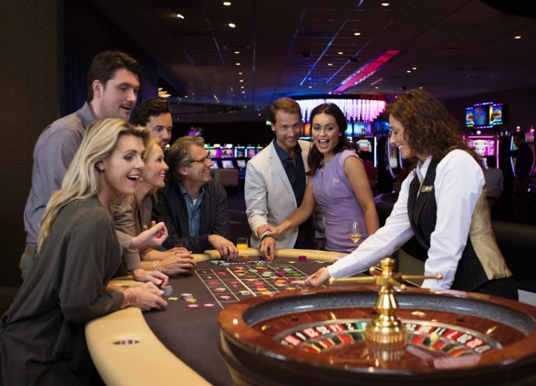 Молодые люди играют в казино в компании дилера