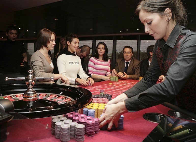 Дилер с клиентами за игрой на рулетке в казино