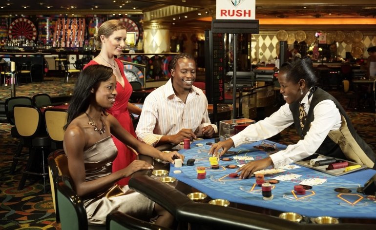 Привлекательная блондинка и ее друзья, темнокожая девушка и парень, играют в блэкджек в казино Туниса